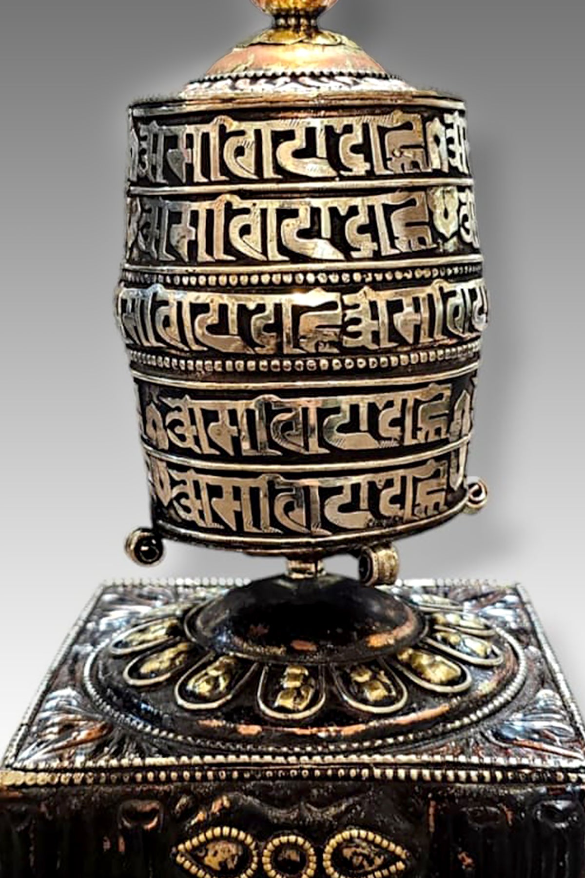 Silver colored ovel Shaped Copper Prayer Wheel in Square base, 9"